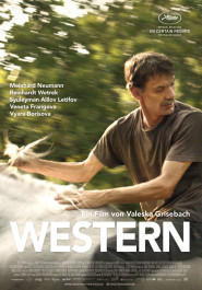 Filmplakat zu "Western". Ein mittelalter Mann mit dunklem Haar, Dreitagebart und grünem T-Shirt hält die Hände zur Seite auf etwas weißem, dahinter ist es unscharf.