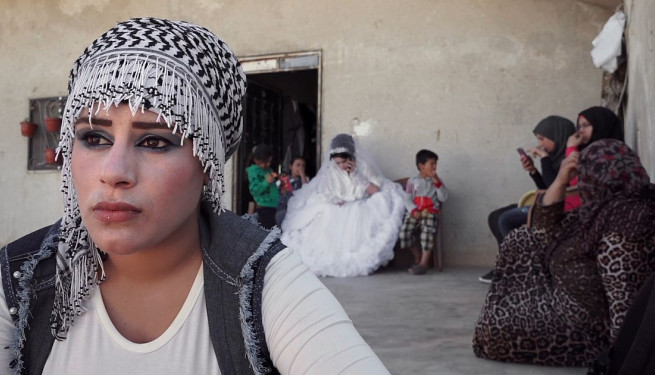 Eine junge Frau mit schwarz-weiß gemustertem Kopftuch und weißem Oberteil.