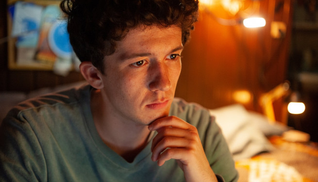 Foto aus "How to sell drugs online (fast)". Ein junger Mann mit dunklem vollen Haar schaut konzentriert nach vorne und hält seine Hand ans Kinn.